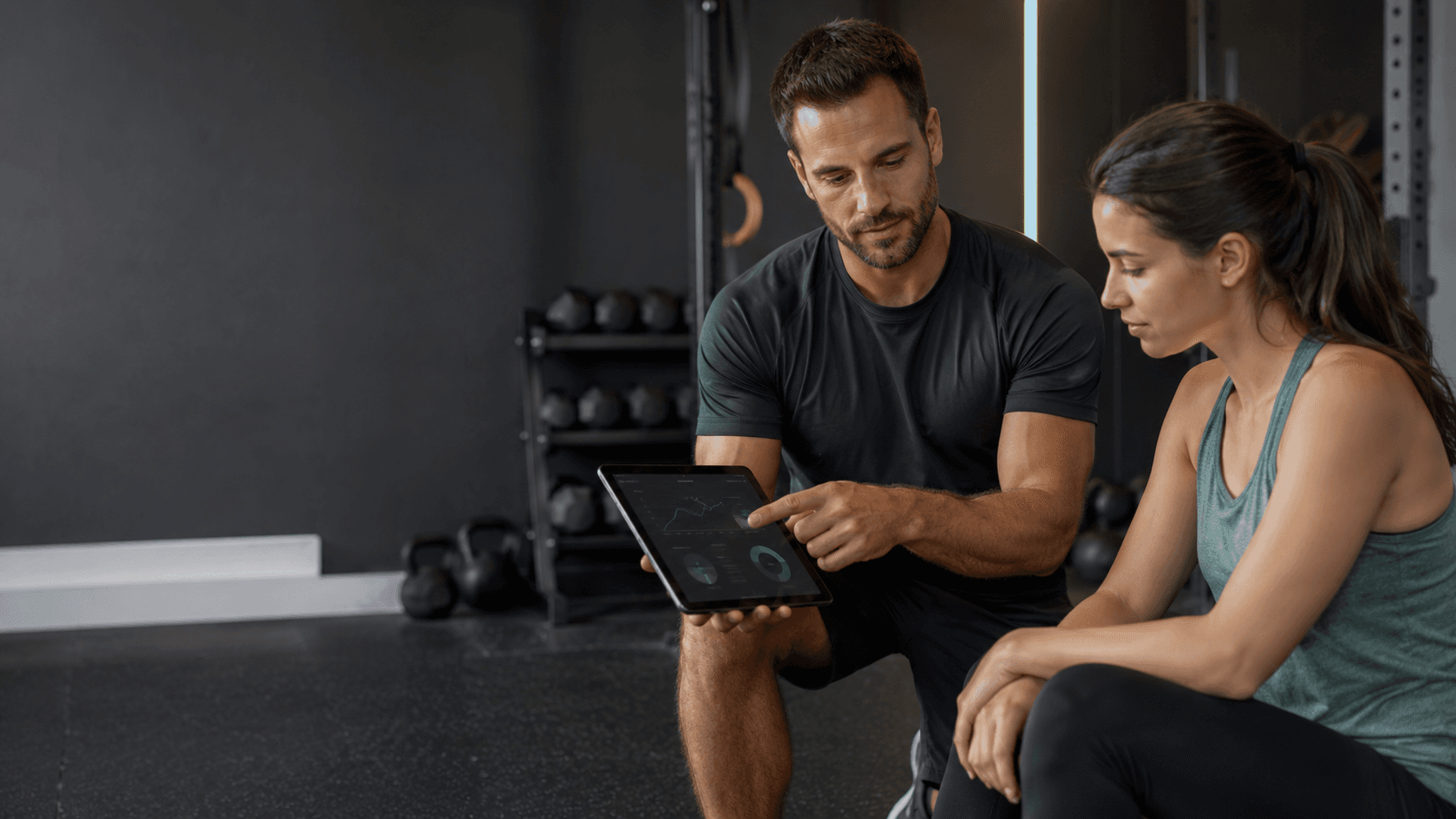 Qué es un entrenador personal y qué debería hacer por ti Entrenador personal explicando a una clienta un plan de entrenamiento individual en una tableta